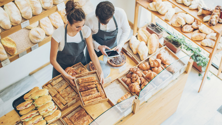 Bakers putting out bread in bakery shop