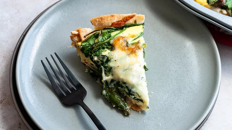 slice of spinach quiche on plate with fork