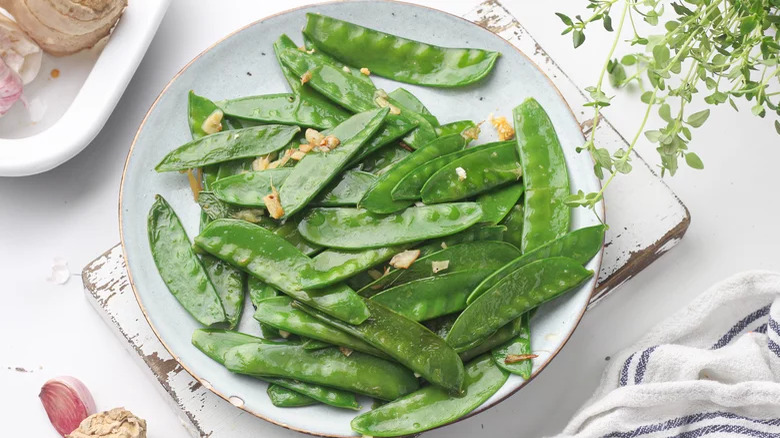 plate of flash-fried snow peas on wood platter