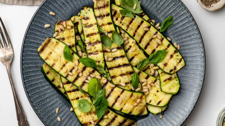 plate of griled zucchini with basil pine nuts fork