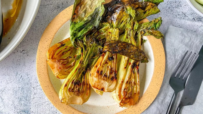 grilled bok choy on plate with fork and knife