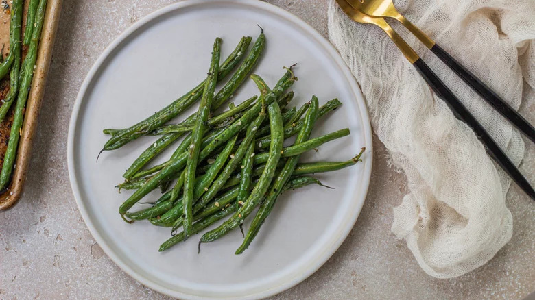 roasted green beans on plate with gold forks on side