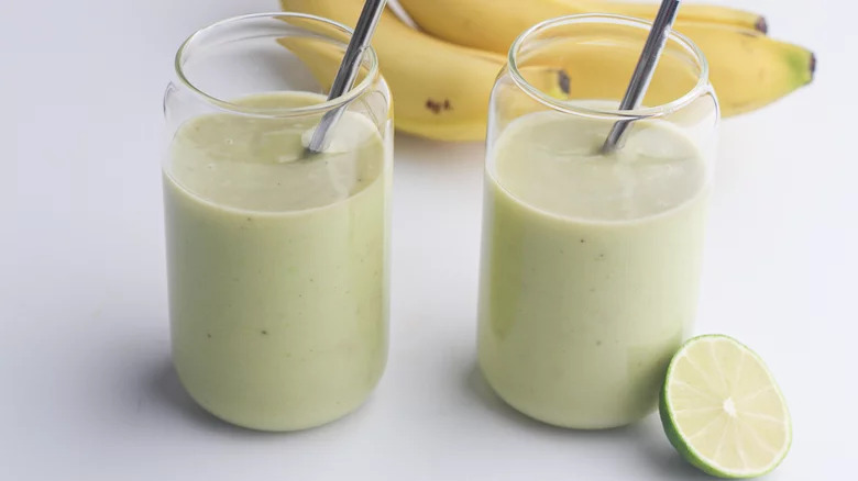 glasses of banana avocado smoothie with straws bananas lime