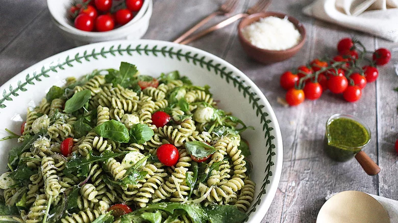 bowl of pesto pasta salad with tomatoes and pesto on side