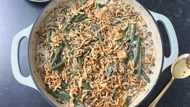 green bean casserole in dutch oven with spoon on side