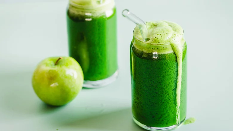 glasses of green juice with straw and granny smith apples