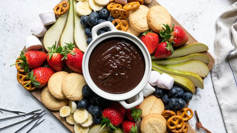 Chocolate fondue with fruits, cookies and pretzels