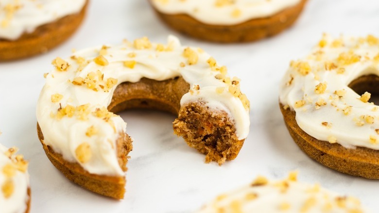 broken-open frosted donut with nuts