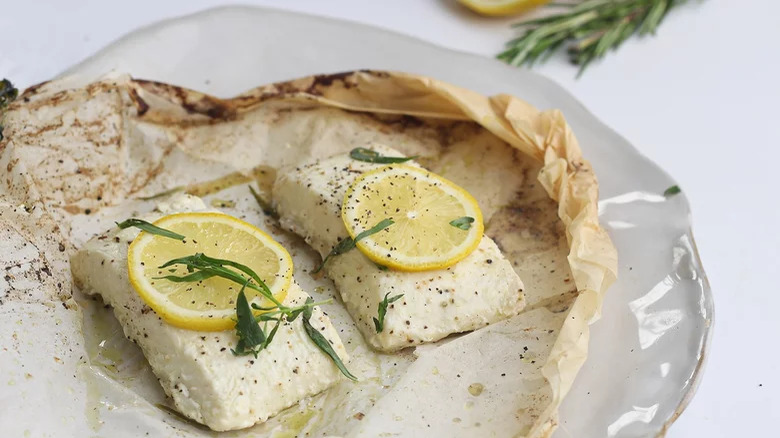 halibut parcels on plate with lemon slices and tarragon 