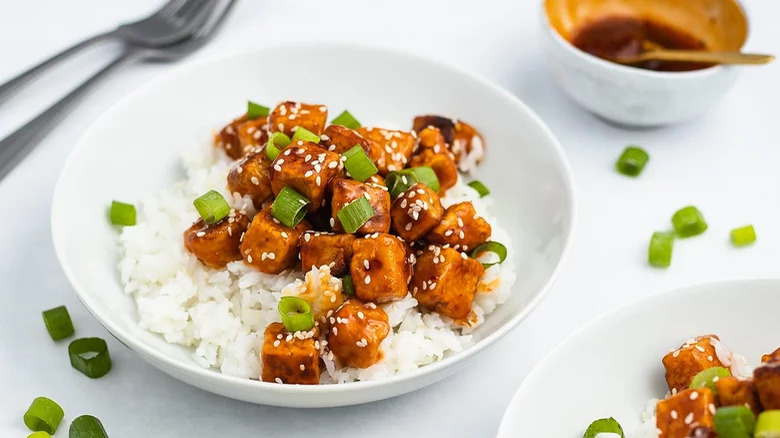 bowl of crispy chilli tofu with white rice and green onions