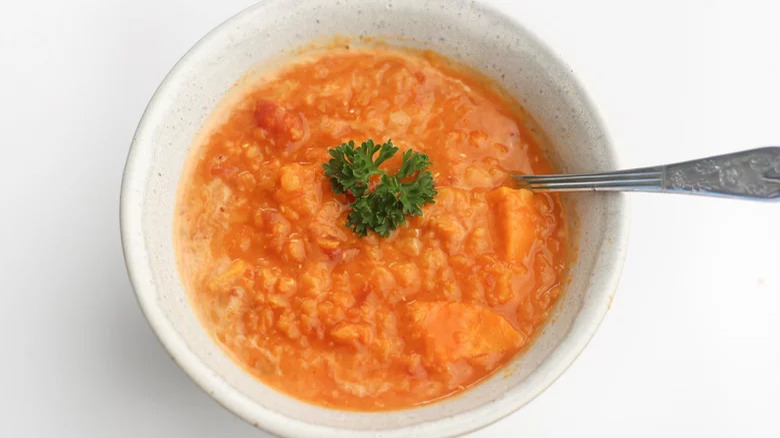 bowl of red lentil soup with spoon and garnish