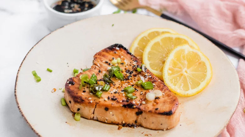 plate with tuna steak and sliced lemon