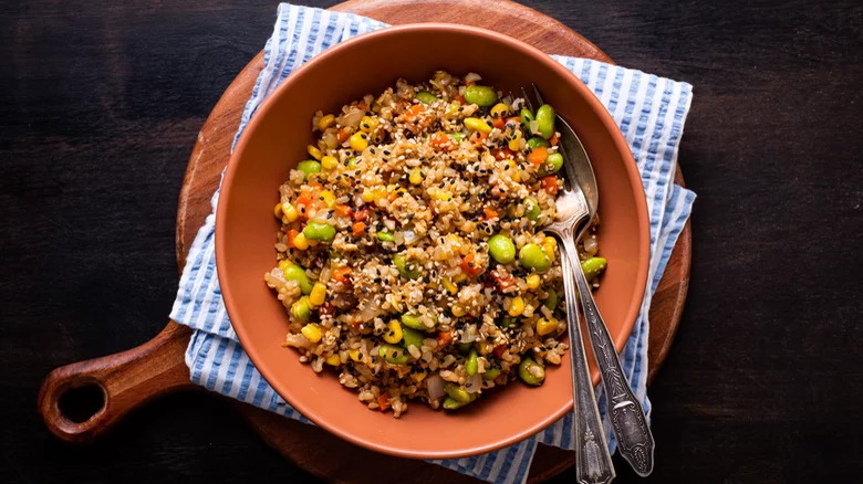 bowl of fried brown rice with fork and spoon