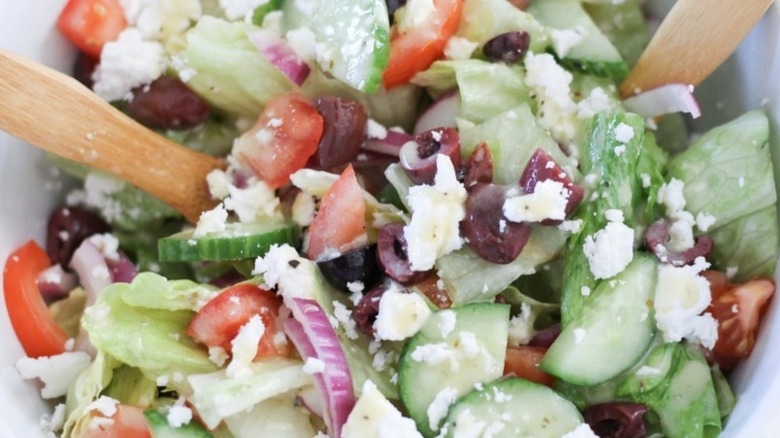 close up of greek salad with wooden utensils