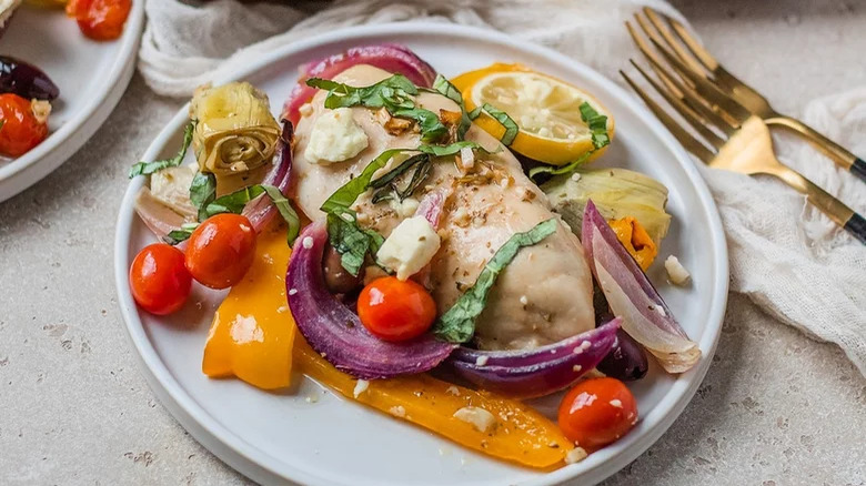 plate of greek sheet pan chicken with vegetables and forks