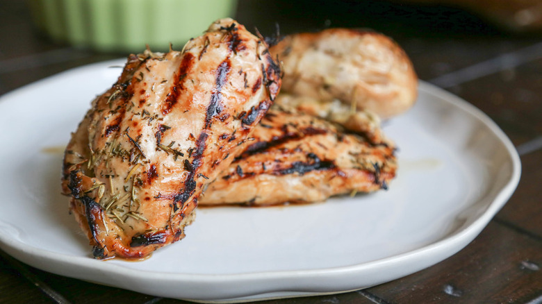 plate of grilled chicken covered in herbs