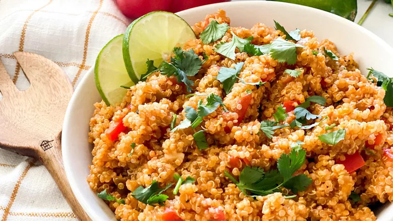 bowl of quinoa spanish rice with lime slices wooden spoon