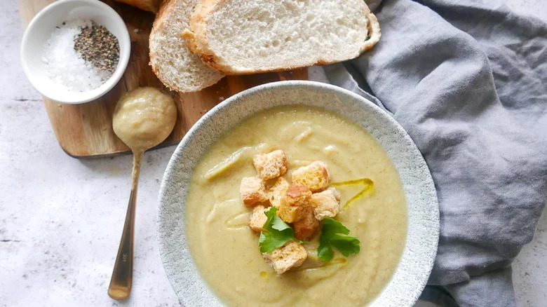 bowl of instant pot broccoli cauliflower soup with spoon bread salt and pepper