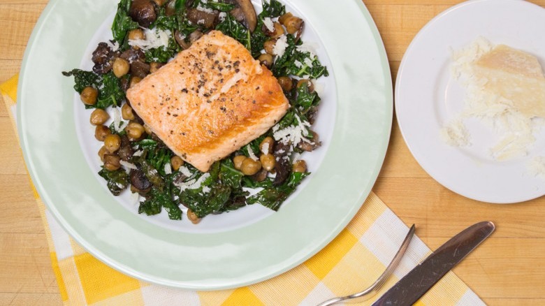 plate of seared salmon with chickpeas and kale knife and fork