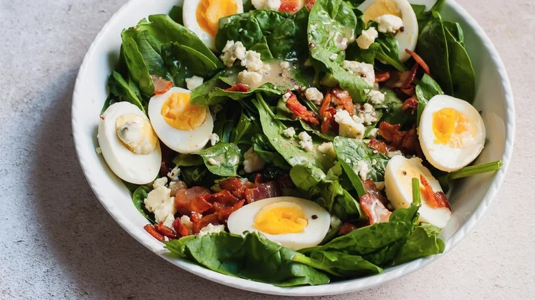 bowl of warm spinach salad with hard boiled egg