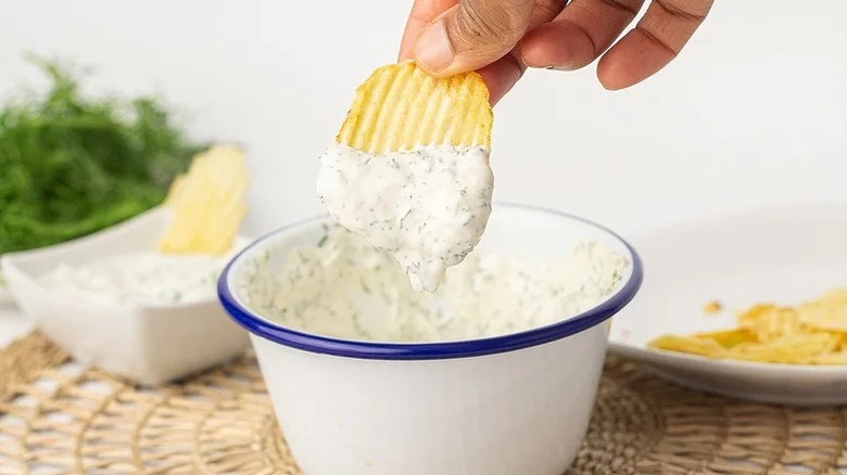 person dipping chip in dip