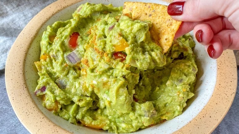 dipping tortilla chip into guacamole