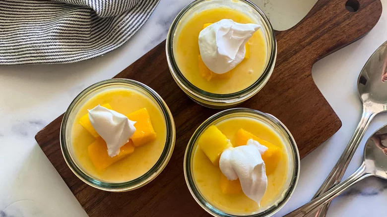 Bowls of mango pudding on a wooden board