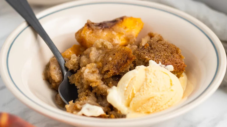 A bowl of peach pudding with ice cream