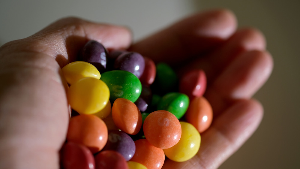 A hand holding some Skittles