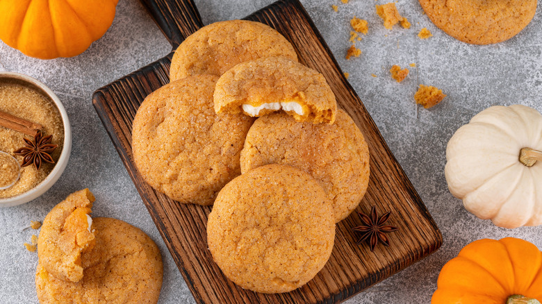 Pumpkin cookies with cream cheese filling on wooden board