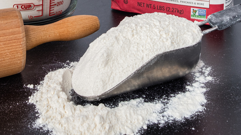 Large scoop holding white flour on table