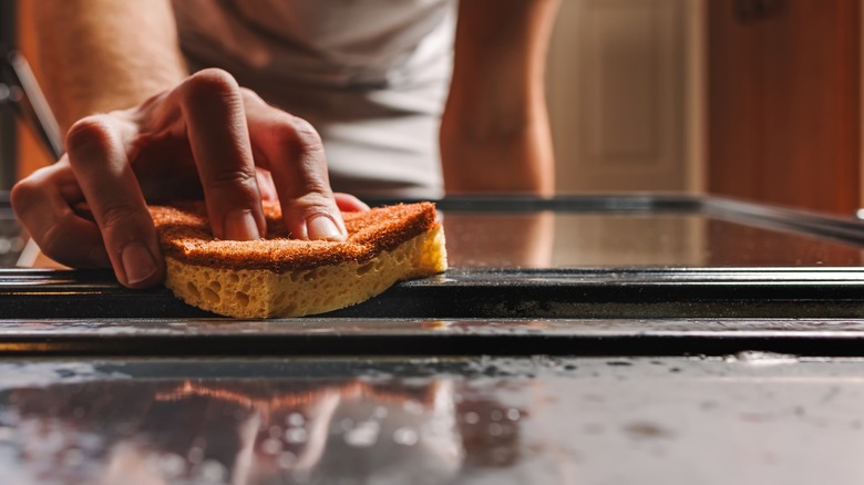 Person scrubbing inside of oven with sponge