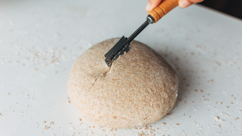 hand scoring dough with razor