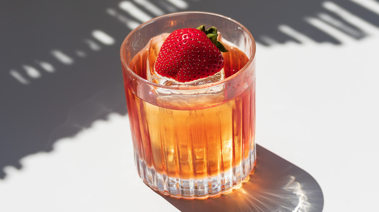 Cocktail with ice cube, strawberry