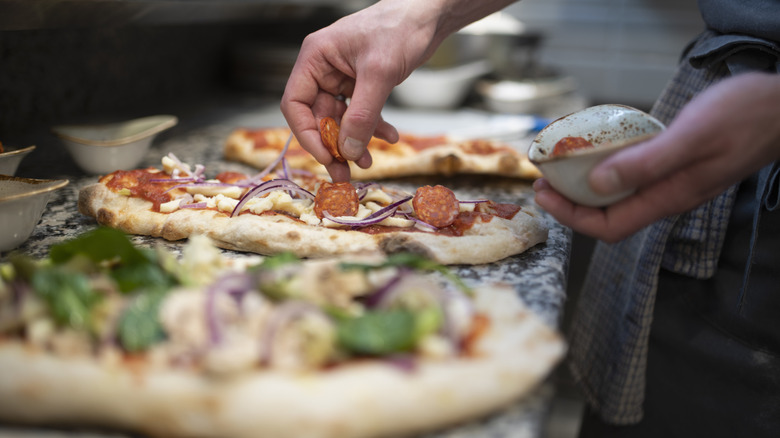 Person adding meat to pizza