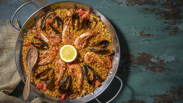 overhead view of seafood paella with fresh ingredients on a dark background