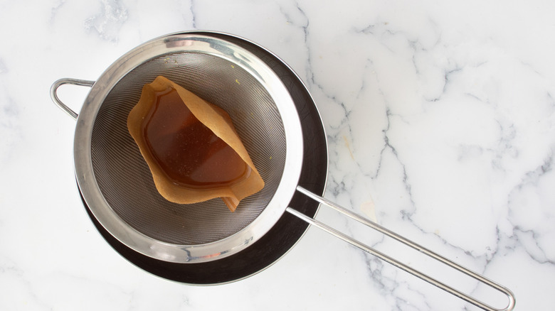 brown paper and brown liquid in a metal strainer