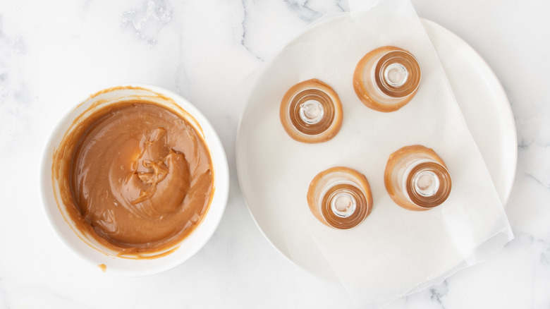 creamy brown sauce in a white bowl next to a plate of shot glasses