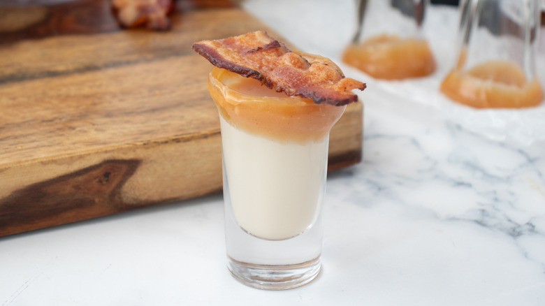 cream drink in caramel-rimmed glass garnished with bacon strip