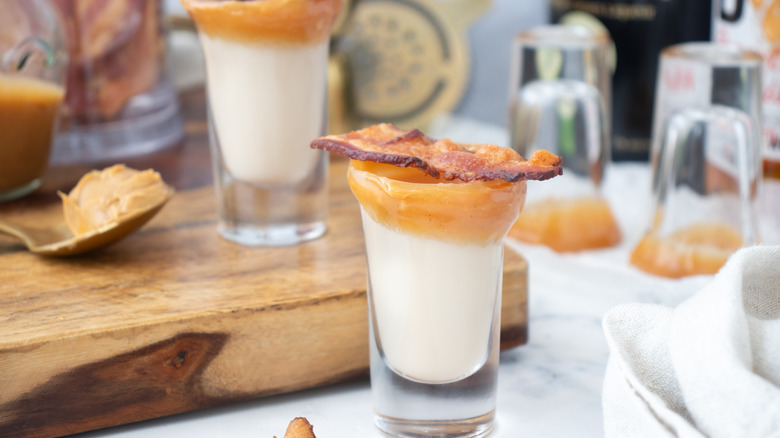 cream drinks in caramel-rimmed glasses garnished with bacon strips