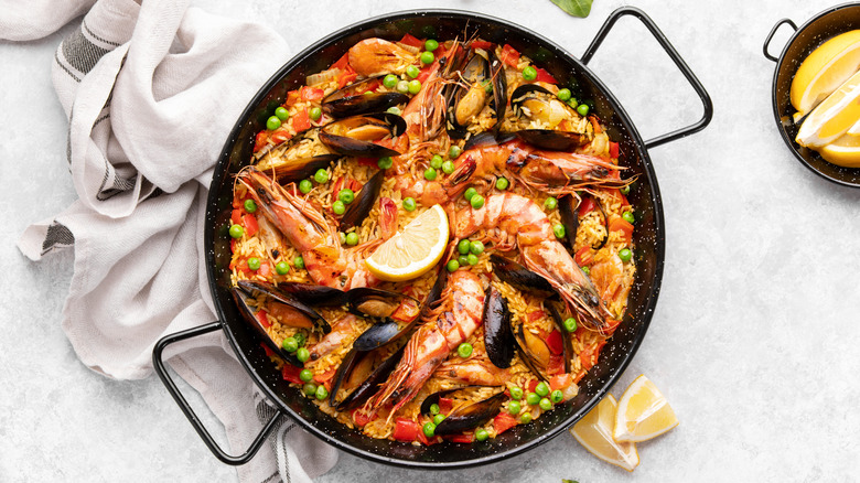 Spanish seafood paella in pan ready to serve with a side of lemons