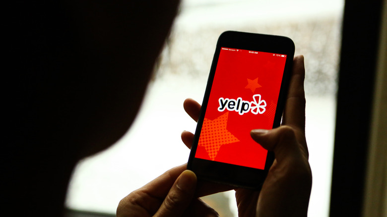 a person pulls up yelp app on phone