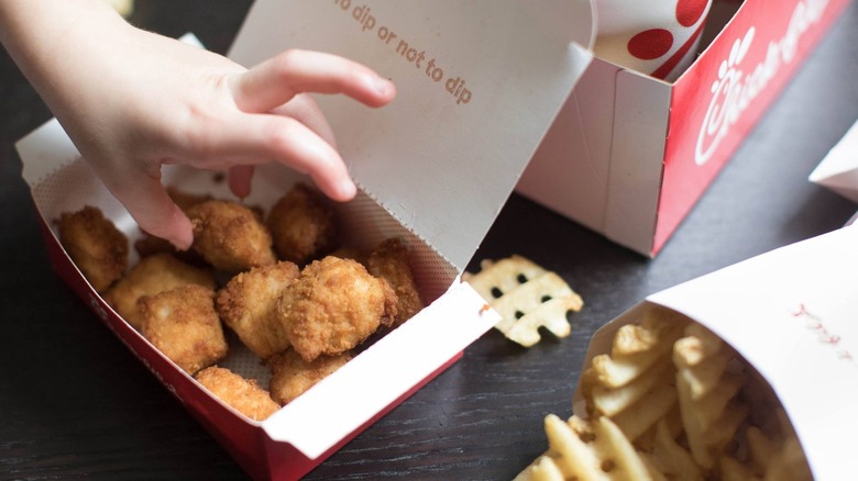 Child reaching for box of Chick-fil-A chicken nuggets