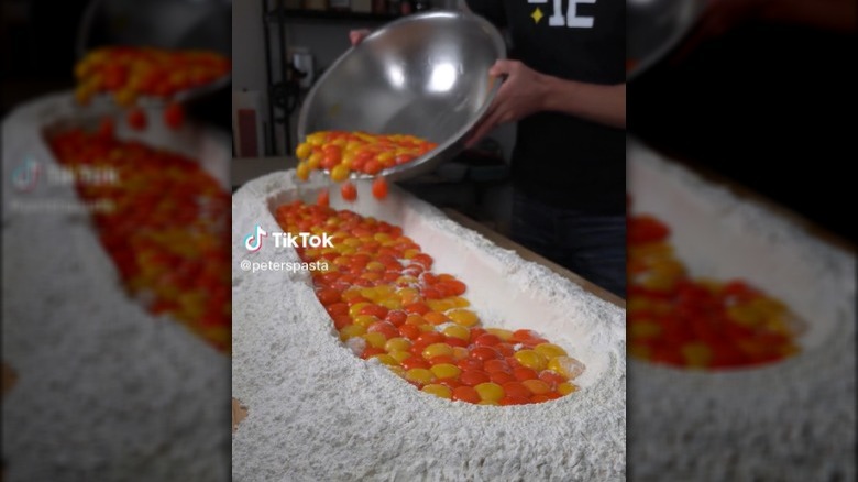 Pouring egg yolks into flour