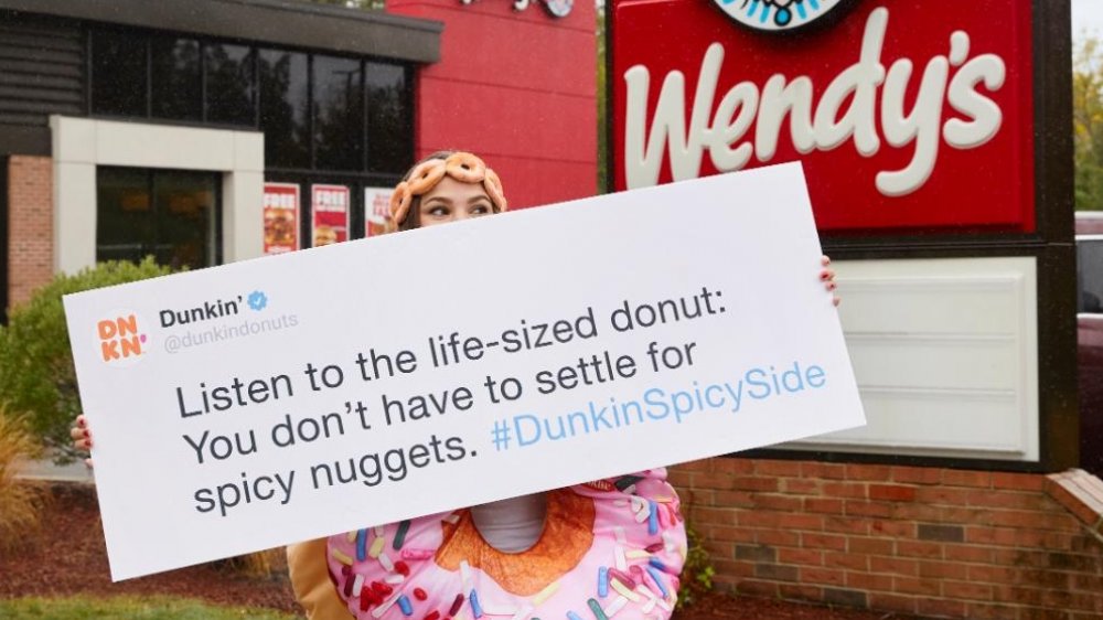 Person in donut costume advertising Dunkin' in front of Wendy's