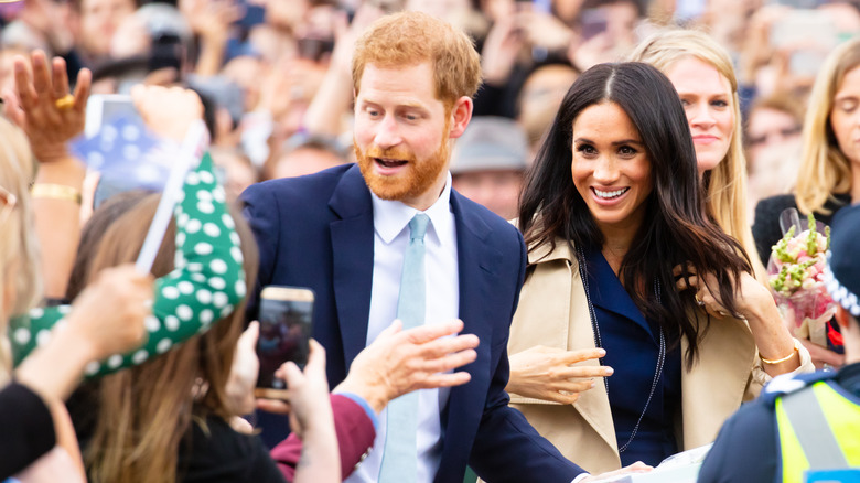 Prince Harry and Meghan Markle surrounded by people taking photos