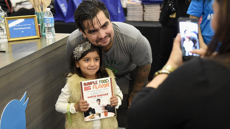Chef aaron sanchez with young fan holding cookbook