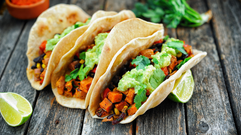 three tacos on wooden table