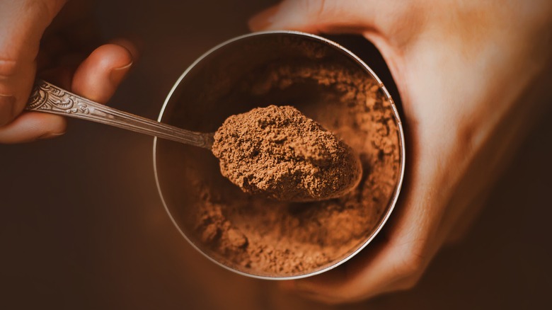 Person holding spoon of hot chocolate mix