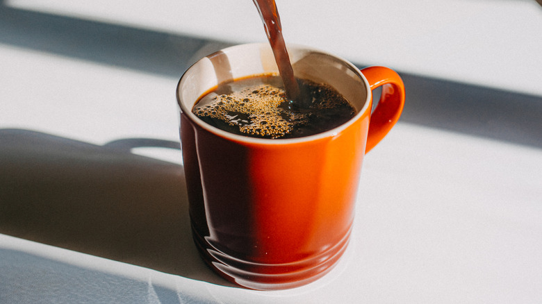 Coffee pouring into orange mug